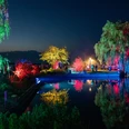 Lichternacht im Zwischenahner Kurpark Das Bild zeigt eine nächtliche Szene im Zwischenahner Kurpark, wo buntes Licht Bäume und Wasser in lebendige Farben taucht. Die Reflexionen erzeugen eine faszinierende Symphonie aus leuchtendem Rot, Blau und Grün auf dem ruhigen Teich, während die Silhouetten von Besuchern die Szenerie beleben.The picture shows a nocturnal scene in the Zwischenahn spa gardens, where colorful light bathes trees and water in vibrant colors. The reflections create a fascinating symphony of bright red, blue and green on the calm pond, while the silhouettes of visitors enliven the scenery.Billedet viser en natlig scene i Zwischenahns spahave, hvor det skarpe lys bader træerne og vandet i levende farver. Refleksionerne skaber en fascinerende symfoni af lyse rødt, blåt og grønt i den rolige dam, mens silhuetterne af de besøgende giver liv til sceneriet.De foto toont een nachtelijk tafereel in het kuurpark Zwischenahn, waar helder licht de bomen en het water in levendige kleuren hult. De weerspiegelingen creëren een fascinerende symfonie van helder rood, blauw en groen op de kalme vijver, terwijl de silhouetten van bezoekers het landschap verlevendigen.