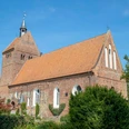 kirchenführung Historische Backsteinkirche mit markantem Kirchturm und rotem Ziegeldach, umgeben von grüner Natur.Historic brick church with striking church tower and red tiled roof, surrounded by green nature.Historisk murstenskirke med markant kirketårn og rødt tegltag, omgivet af grøn natur.Historische bakstenen kerk met opvallende kerktoren en rood pannendak, omgeven door groene natuur.
