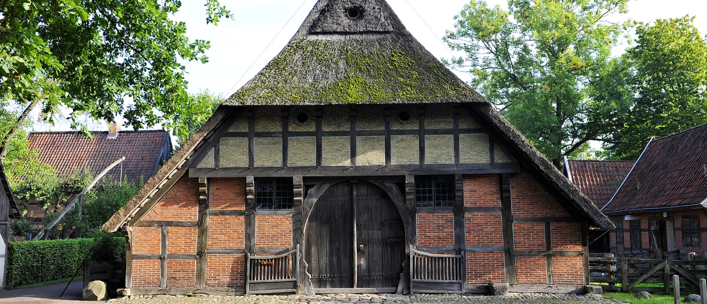 Historisches Fachwerk-Bauernhaus mit Reetdach und großem Holztor in Bad Zwischenahn.