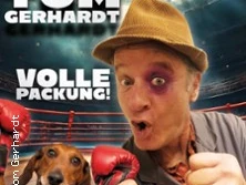 Comedian Tom Gerhardt posiert in Boxpose, ein Hund trägt rote Boxhandschuhe, im Hintergrund der Boxring.
