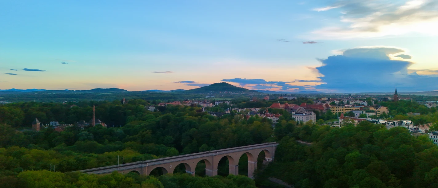 Görlitz 2024_c_TMGS_Fravely (8).jpeg Luftaufnahme von Görlitz bei Sonnenuntergang mit markantem Viadukt und grüner Umgebung.
