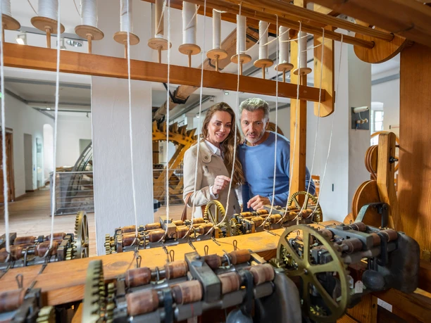 LVR-Industriemuseum - Textilfabrik Cromford Zwei Personen betrachten alte Spinnmaschinen in der historischen Textilfabrik Cromford des LVR-Industriemuseums.