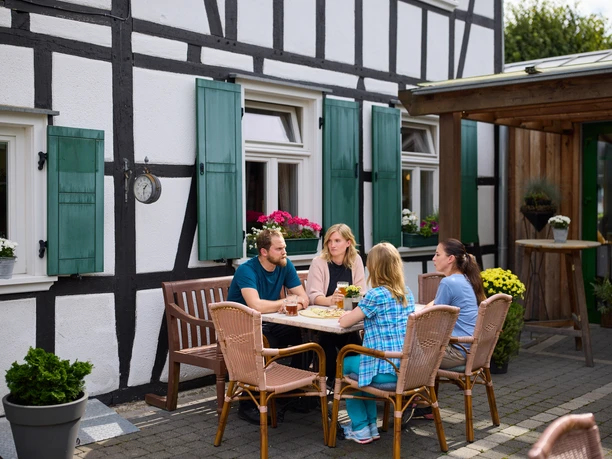 Restaurant Zur Post Vier Personen sitzen an einem Tisch vor einem Fachwerkhaus und genießen gemeinsam eine Mahlzeit.