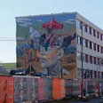 Mural Auf dem Bild ist eine farbenfrohe Wandmalerei zu sehen, die ein surrealistisches Motiv mit Figuren, Tieren und Landschaften darstellt.The picture shows a colorful mural depicting a surrealistic motif with figures, animals and landscapes.