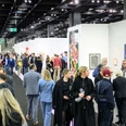 ART COLOGNE Menschen flanieren entlang der Stände, betrachten aufmerksam verschiedene Kunstwerke, die an weißen Wänden präsentiert werden. Im Vordergrund zieht eine bunte Mischung aus Gemälden die Blicke der Betrachter*innen auf sich, während die Decke durch industrielle Beleuchtung hervorsticht. Die Szene wirkt lebendig und zeigt das Interesse der Menschen an zeitgenössischer Kunst.People stroll along the stands, attentively looking at various works of art presented on white walls. In the foreground, a colorful mixture of paintings catches the viewer's eye, while the ceiling stands out with industrial lighting. The scene looks lively and shows people's interest in contemporary art.