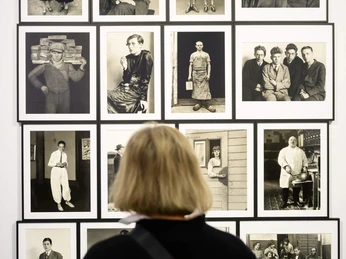 ART COLOGNE Vor einer Wand mit elf Schwarz-Weiß-Fotografien betrachtet eine Person die Exponate.A person looks at the exhibits in front of a wall with eleven black and white photographs.