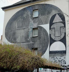 Mural Das beeindruckende Wandgemälde auf dem Gebäude zeigt abstrahierte Formen und Gesichter in Schwarz-Weiß-Tönen.