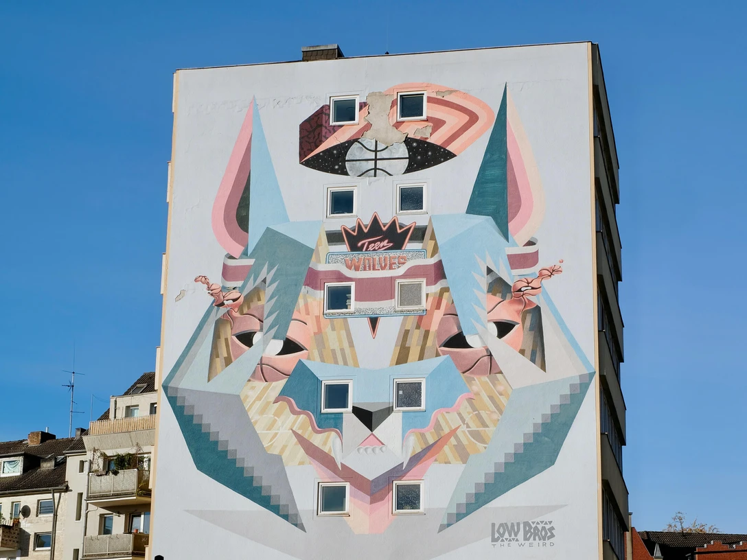 Mural Das Bild zeigt ein beeindruckendes Wandgemälde in Köln. Es stellt ein stilisiertes Wolfsdesign dar, das in einer modernen, geometrischen Art gestaltet ist. Die verwendeten Farben und Formen erzeugen einen dynamischen und urbanen Look, der die Kreativität und Vielfalt der Stadt widerspiegelt.The picture shows an impressive mural in Cologne. It depicts a stylized wolf design created in a modern, geometric style. The colors and shapes used create a dynamic and urban look that reflects the creativity and diversity of the city.