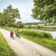 Am Fünf-Flüsse-Radweg bei Krachenhausen Zwei Radfahrer auf einem geschotterten Abschnitt des Fünf-Flüsse-Radwegs fahren entlang der Naab bei Krachenhausen