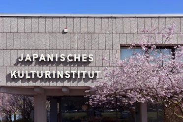 Japanisches Kulturinstitut Das Japanische Kulturinstitut zeigt seine Fassade, flankiert von blühenden Kirschbäumen im Frühling.
