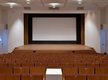 Stage of the Japanese Cultural Institute Holzvertäfelte Bühne im Japanischen Kulturinstitut mit Leinwand und roten Sitzplätzen.Wood-paneled stage in the Japanese Cultural Institute with screen and red seats.
