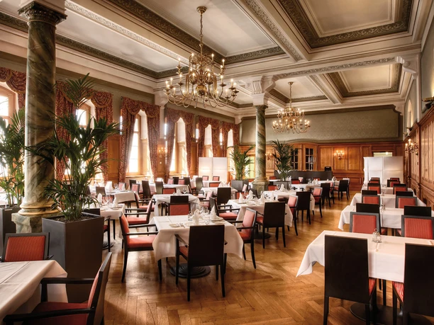 Eleganter Speisesaal im Pilatus Kulm Hotel mit Kronleuchtern, Säulen und gedeckten Tischen