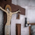 Evangelische Kirche Eidinghausen Destination one.png Kruzifix aus Holz mit Jesus-Figur, Hintergrund wirkt rustikal mit einem verschwommenen Bildrahmen.