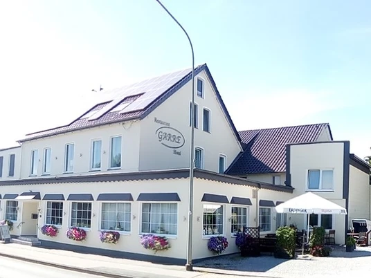 Ein zweistöckiges Restaurant mit hellen Wänden, Fenstern in Reih und Solarzellen auf dem Dach.