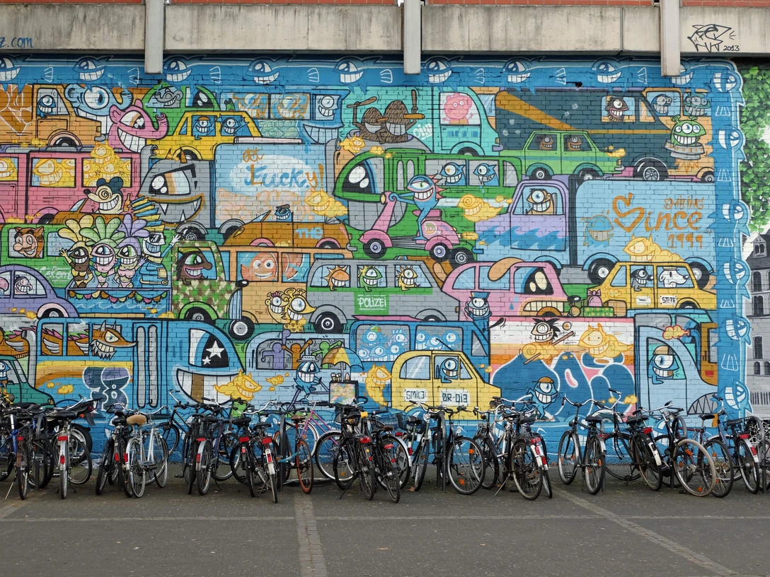 Mural Buntes Mural mit vielen fröhlich gezeichneten Autos, darunter parkende Fahrräder.Colorful mural with lots of cheerfully drawn cars, including parked bicycles.