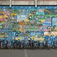 Mural Buntes Mural mit vielen fröhlich gezeichneten Autos, darunter parkende Fahrräder.Colorful mural with lots of cheerfully drawn cars, including parked bicycles.