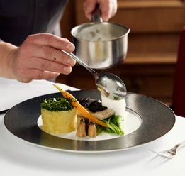 Gasthaus Buschkamp Bielefeld Ein Gourmetgericht wird kunstvoll mit einer Schaumsoße verfeinert, auf elegantem Porzellanteller.