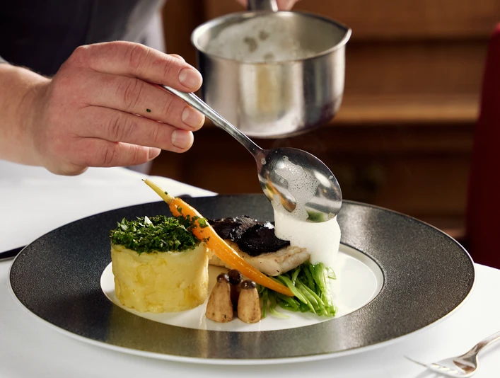 Gasthaus Buschkamp Bielefeld Ein Gourmetgericht wird kunstvoll mit einer Schaumsoße verfeinert, auf elegantem Porzellanteller.