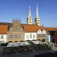 Marktplatz Lemgo mit Fachwerkhäusern, hohen Kirchtürmen und belebten Café-Tischen bei Sonnenschein.