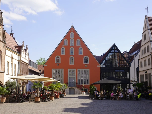 Marktplatz Lemgo Ballhaus Marktplatz in Lemgo mit rötlichem Ballhaus, Sitzgelegenheiten und umgeben von historischen Gebäuden.