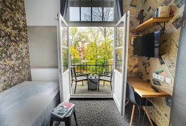 Ein modernes Hotelzimmer mit Balkonblick auf grüne Baumkronen und komfortabler Ausstattung.