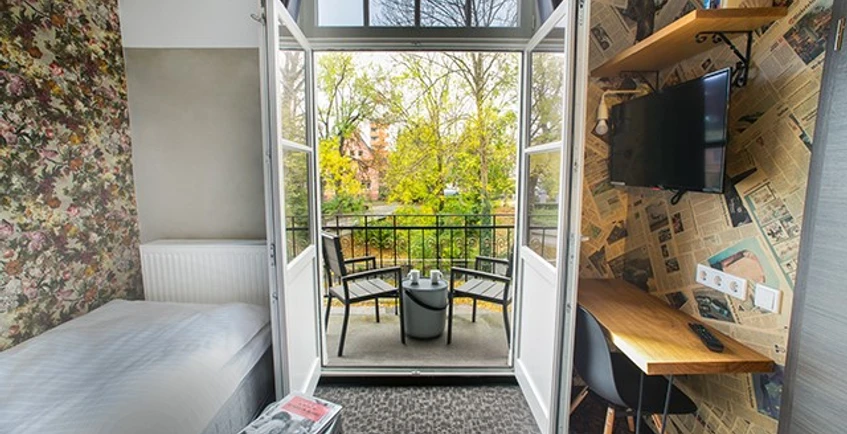 Ein modernes Hotelzimmer mit Balkonblick auf grüne Baumkronen und komfortabler Ausstattung.