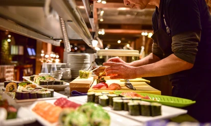 Küche Land Gut Höhne Ein Koch bereitet Sushispezialitäten auf einer offenen Theke in einem gehobenen Restaurant vor.