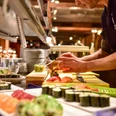 Küche Land Gut Höhne Ein Koch bereitet Sushispezialitäten auf einer offenen Theke in einem gehobenen Restaurant vor.