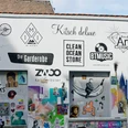 Körnerfeld Auf dem Bild ist ein Abschnitt einer kreativ gestalteten Wand in urbanem Umfeld zu sehen. Die Wand ist mit einer Vielzahl von bunten Postern, Schildern und Graffiti bedeckt. Einige der Logos und Schilder bewerben lokale Geschäfte.The picture shows a section of a creatively designed wall in an urban environment. The wall is covered with a variety of colorful posters, signs and graffiti. Some of the logos and signs advertise local businesses.