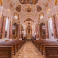 Führung durch die Frauenkirche in Günzburg Prächtige Innenansicht der Frauenkirche in Günzburg mit barocken Holzbänken und kunstvollen Fresken.