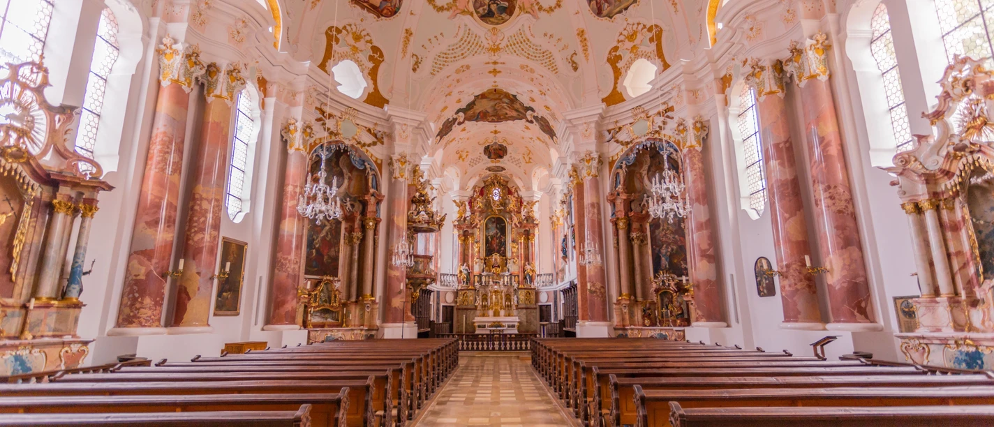 Führung durch die Frauenkirche in Günzburg Prächtige Innenansicht der Frauenkirche in Günzburg mit barocken Holzbänken und kunstvollen Fresken.