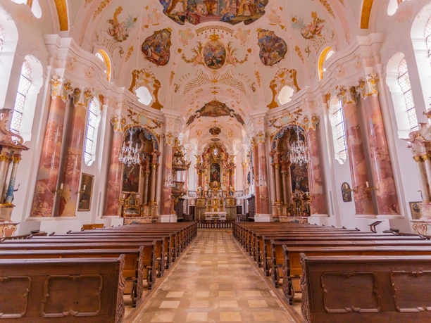 Führung durch die Frauenkirche in Günzburg Prächtige Innenansicht der Frauenkirche in Günzburg mit barocken Holzbänken und kunstvollen Fresken.