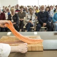 Fischkochstudio Koch präsentiert frisches Lachsfilet vor interessiertem Publikum in moderner Showküche.