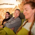 Salzgrotte im Landhotel Annelie Vier Personen entspannen auf Liegestühlen, umgeben von Salzsteinwänden in einer beruhigenden Atmosphäre.