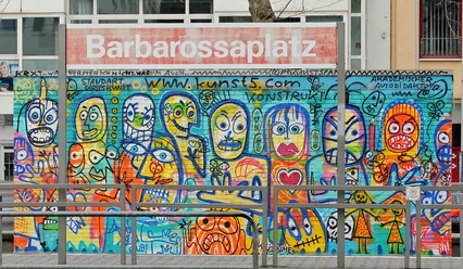 Mural Das Bild zeigt eine bunte Wand voller fantasievoller Graffiti-Figuren am Barbarossaplatz in Köln.