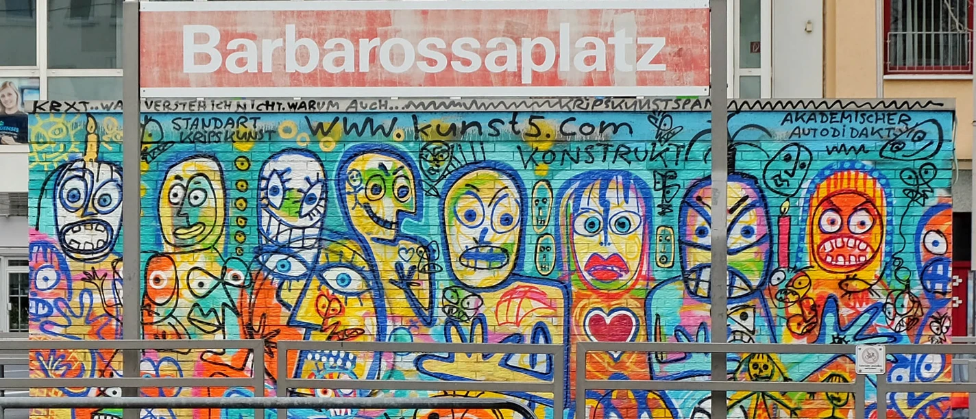 Mural Das Bild zeigt eine bunte Wand voller fantasievoller Graffiti-Figuren am Barbarossaplatz in Köln.