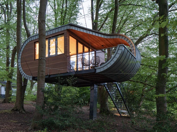 Baumhaus im Hochseilgarten K1 Ein modernes Baumhaus mit Holzverkleidung und Panoramafenstern, umgeben von dichtem Wald.