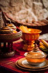 Traditionelle thailändische Speisen in kunstvoll verzierten Porzellanschalen auf einem gewebten Tuch.
