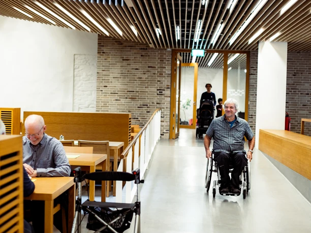 Haus Altenberg Ein barrierefreies Restaurant mit Rollstuhlfahrer, modernen Möbeln und hellem, einladendem Design.