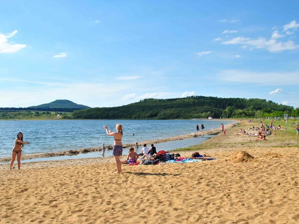 Vor der Kulisse der Landeskrone lässt es sich am Berzdorfer See am Strand entspannen