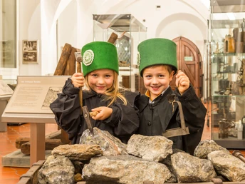 zwei Kinder in Bergbauuniform, an einem Erzhunt in der Bergbauausstellung des Stadt- und Bergbaumuseums Freiberg stehend