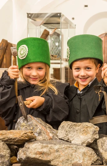 zwei Kinder in Bergbauuniform, an einem Erzhunt in der Bergbauausstellung des Stadt- und Bergbaumuseums Freiberg stehend