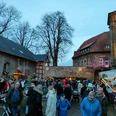 Weihnachtsmarkt Schloss.jpeg Abendlicher Weihnachtsmarkt mit beleuchteten Ständen und Besuchern in historischer Architekturkulisse.