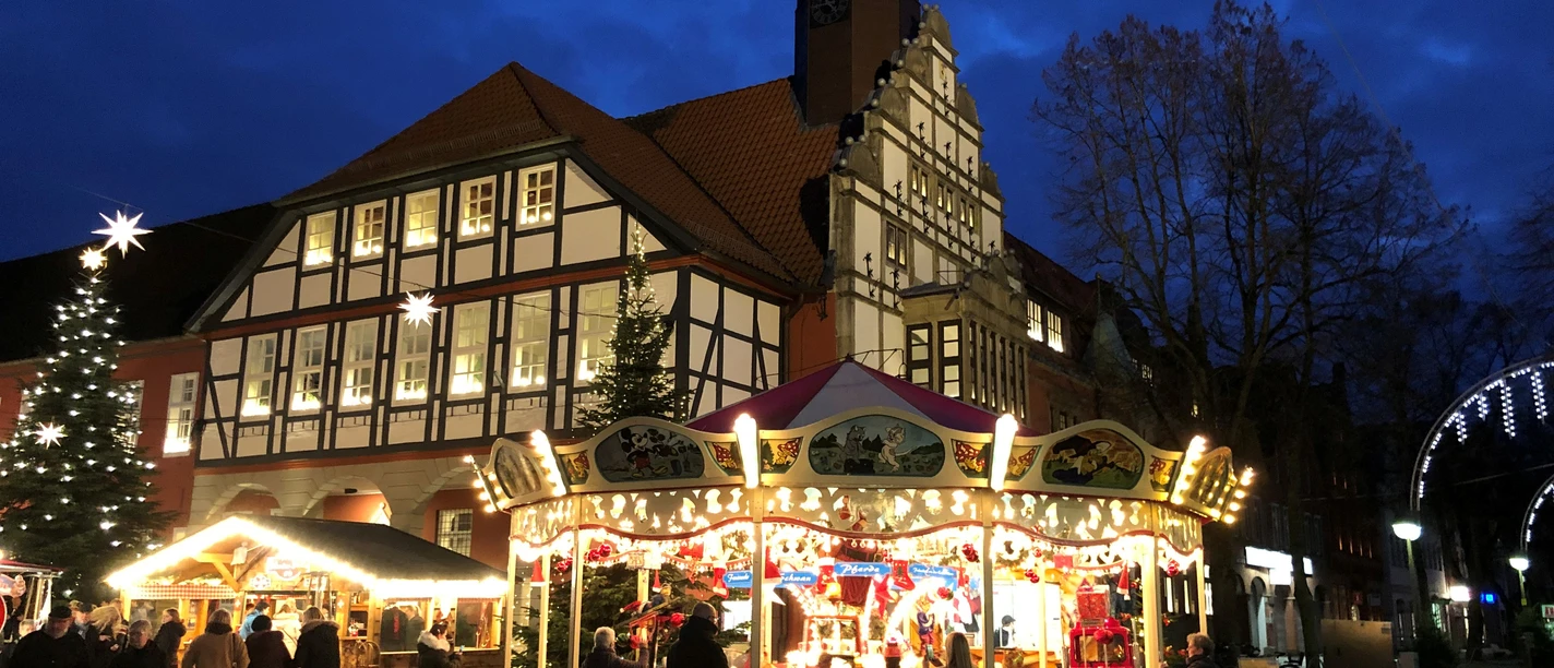 Adventszauber Nienburg (2).jpg Christmas-lit market square in Nienburg with carousel and half-timbered building at dusk.
