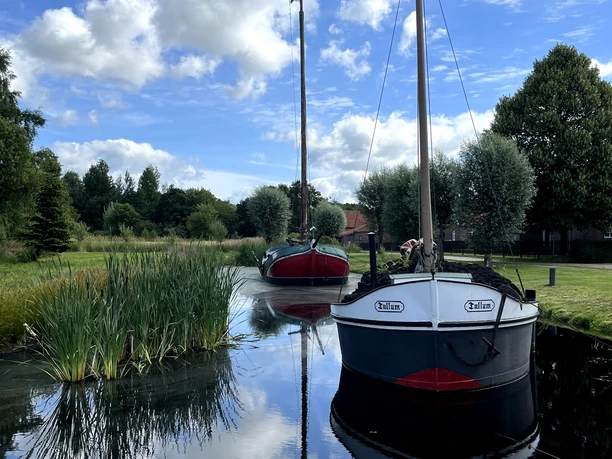 Torfschiffe in Wiesmoor Zwei historische Torfschiffe liegen auf einem schmalen Kanal, umgeben von grüner Wiesenlandschaft.