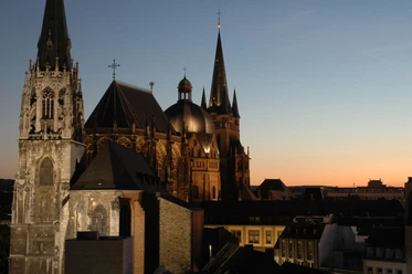 Der beleuchtete Aachener Dom ragt majestätisch in den Abendhimmel.
