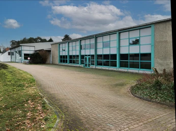 Eingang zum Steimbke-Hallenbad mit großer Glasfront, umgeben von Gehweg und Grünflächen.