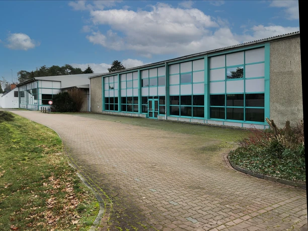 Eingang zum Steimbke-Hallenbad mit großer Glasfront, umgeben von Gehweg und Grünflächen.