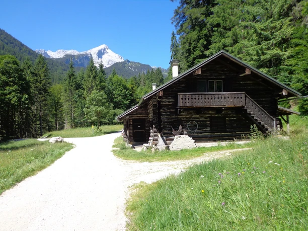Reintal Holzhütte am Waldweg vor bewaldeten Hängen und einem markanten, hellen Bergmassiv im Hintergrund