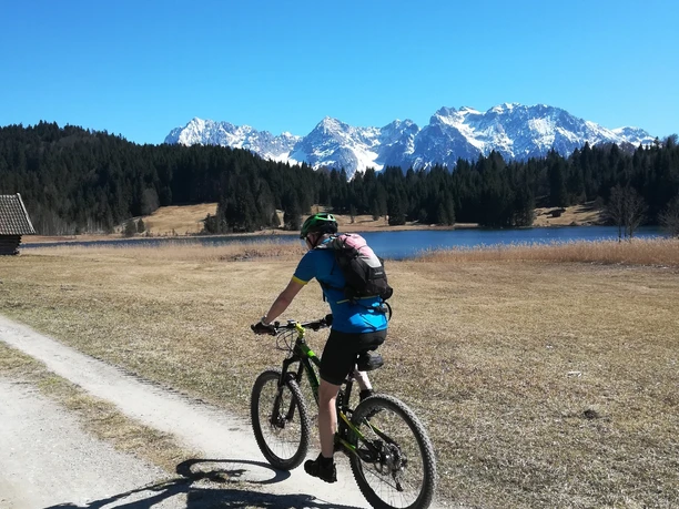 Radfahren am Geroldsee Radfahrer auf Schotterweg am Geroldsee vor schneebedeckten Bergen und klarem Himmel